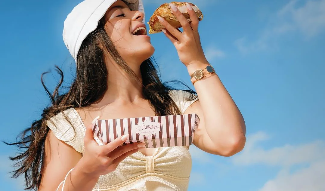 A customer on the Alexandria seafront holding a Sabrina striped pastry box and bag