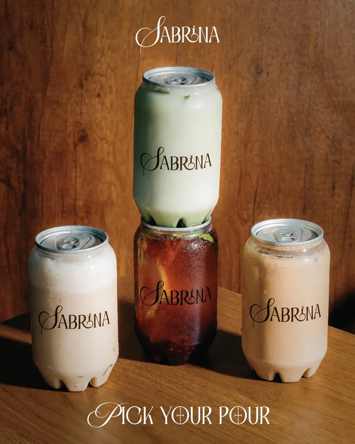 Pick your pour, three Sabrina cans on a wooden counter